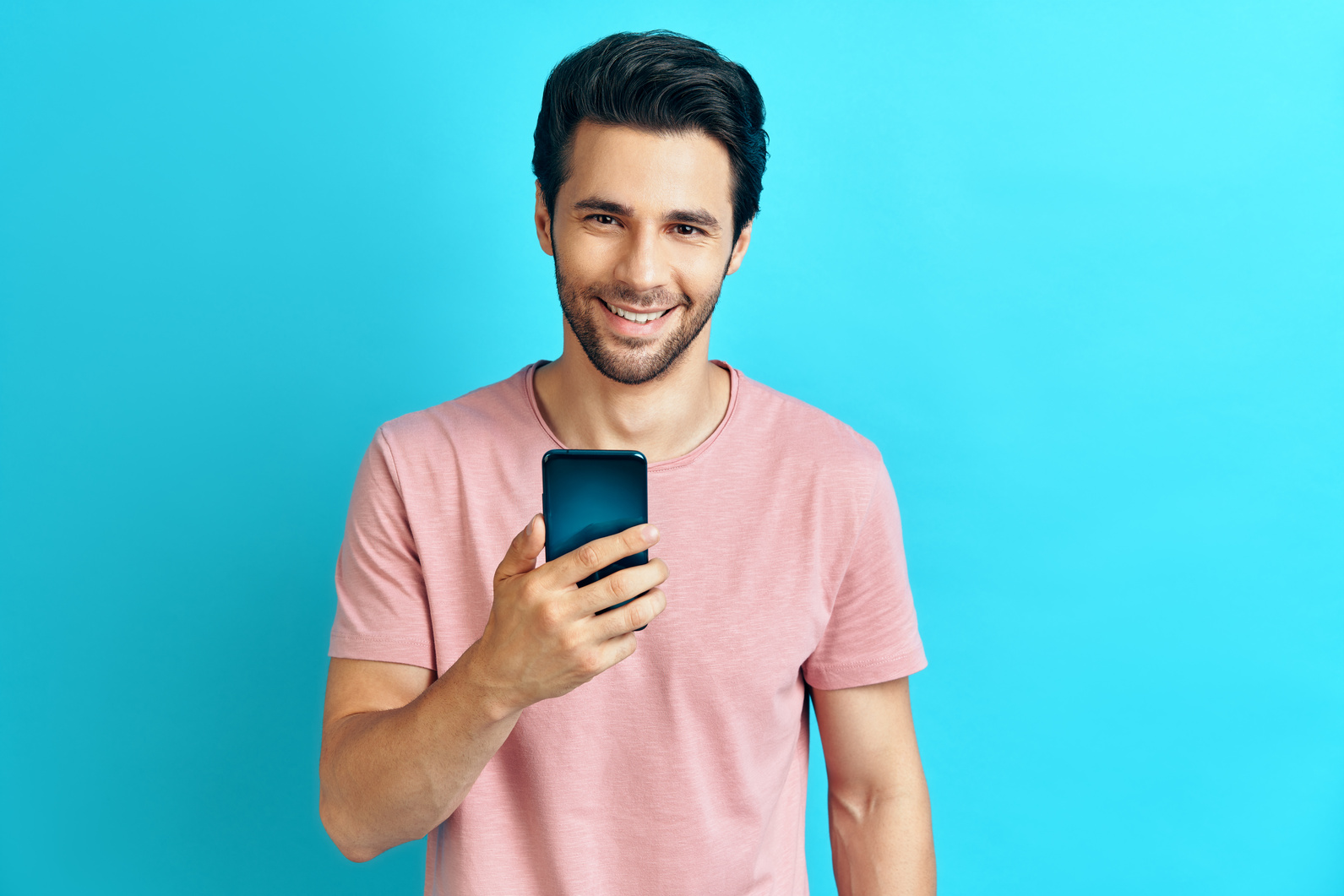 Handsome Smiling Man Holding Mobile Phone on Blue Background 